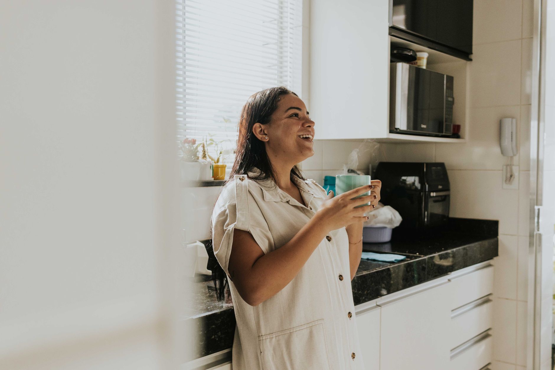 A woman smiling warmly at home with a cup of coffee